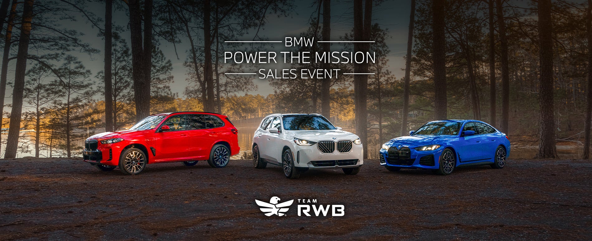Red white and blue BMW parked with a forest landscape.